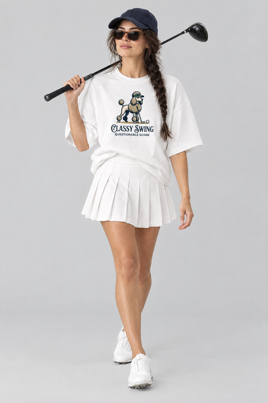 Woman walking with a driver over her shoulder, wearing the Classy Swing Poodle Golf Tee with a navy cap and sunglasses. Color: White