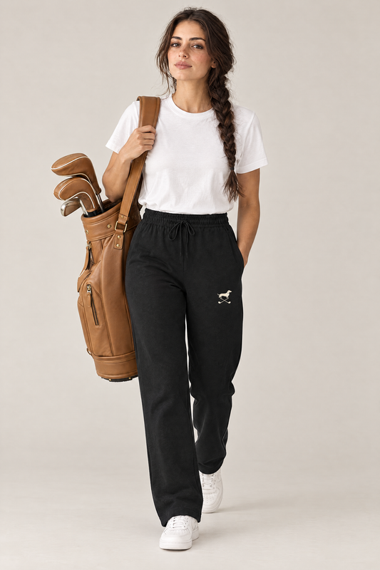 Woman walking with a tan leather golf bag in black Club Mark dachshund golf sweatpants and a white tee. Color: Black