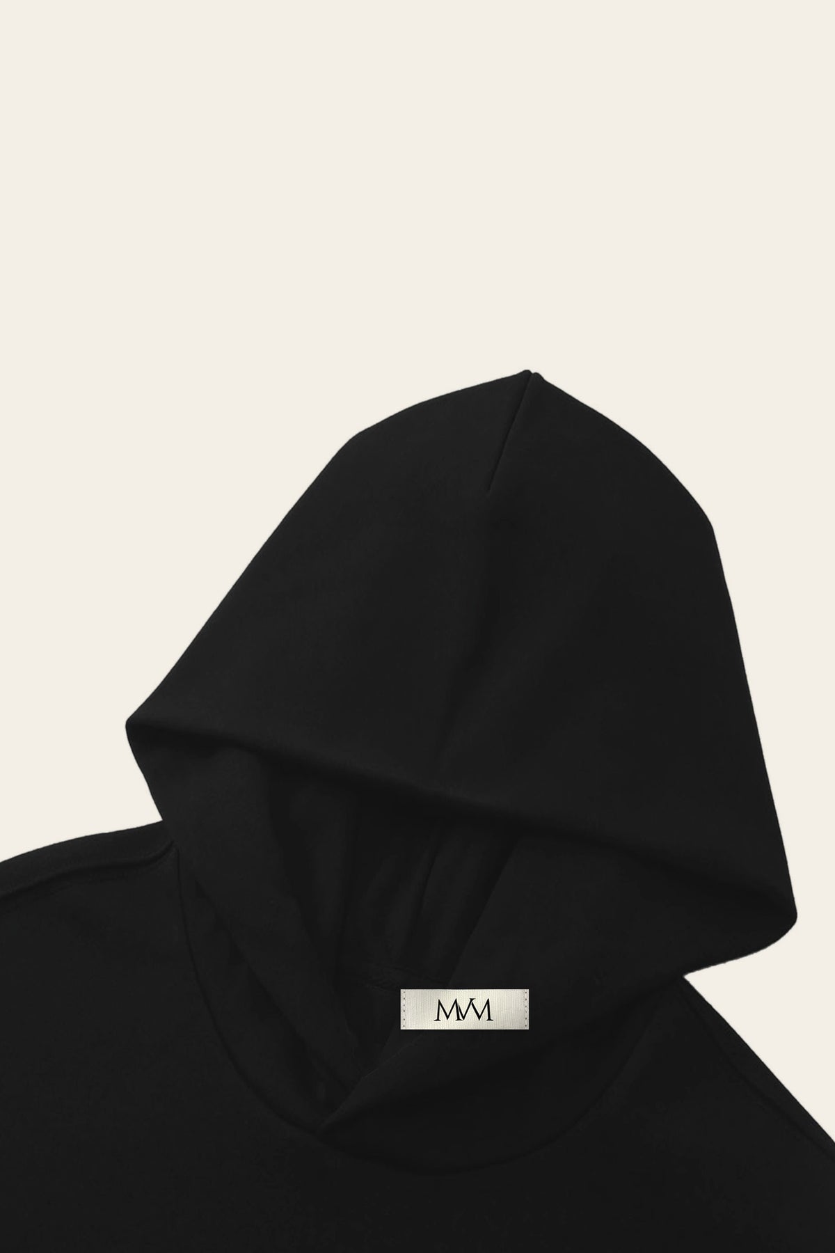 Detail of the hood of the black golf hoodie with the MVM woven neck label. Color: Black