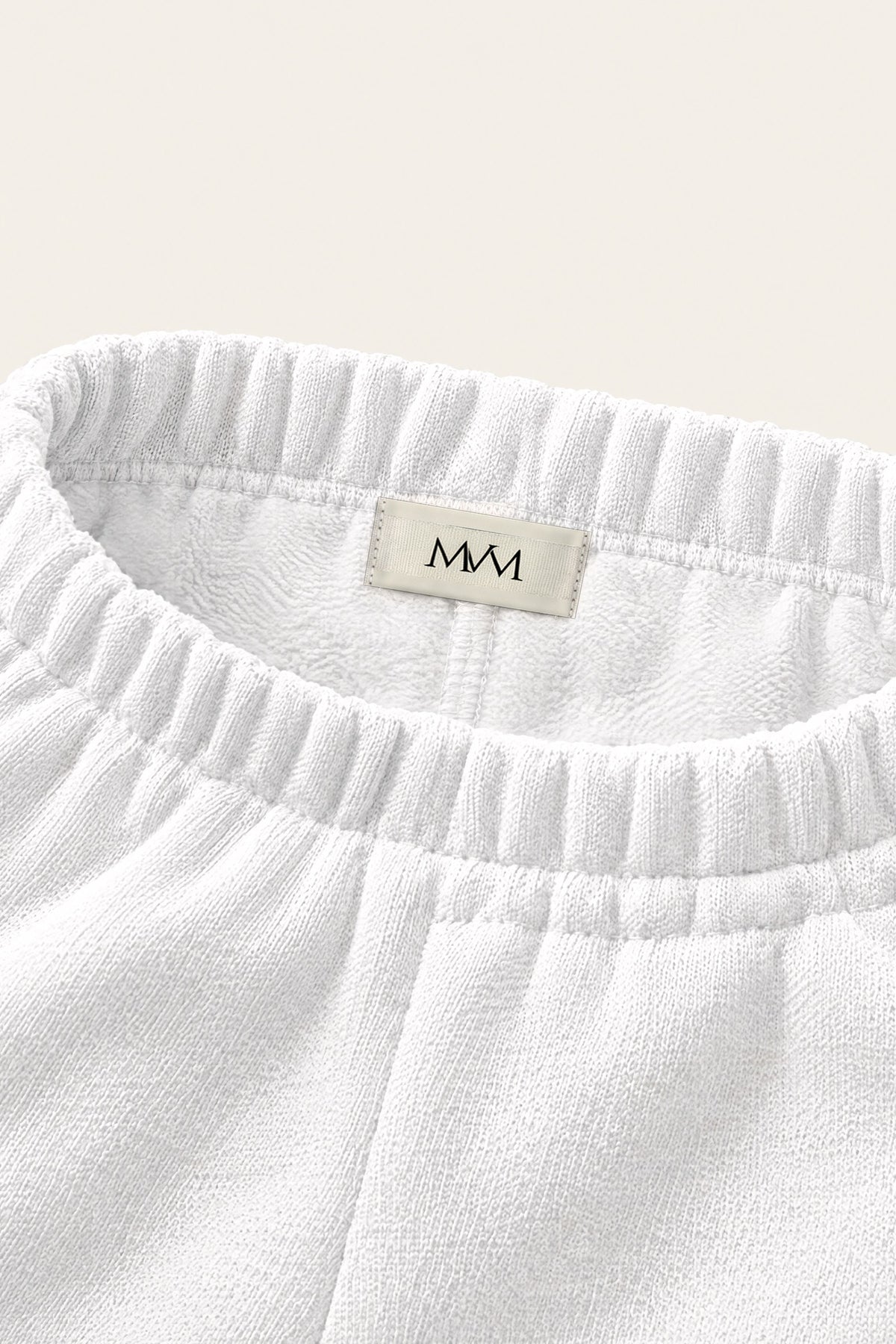 Inside of the back waistband of the white golf sweatpants with the MVM woven label. Color: White