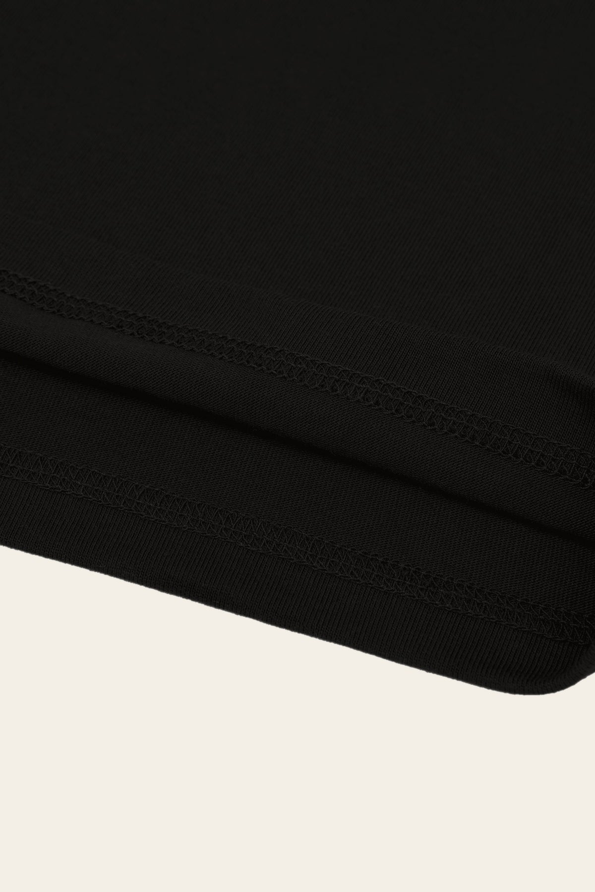 Detail of the stitched hem of the black golf t-shirt. Color: Black