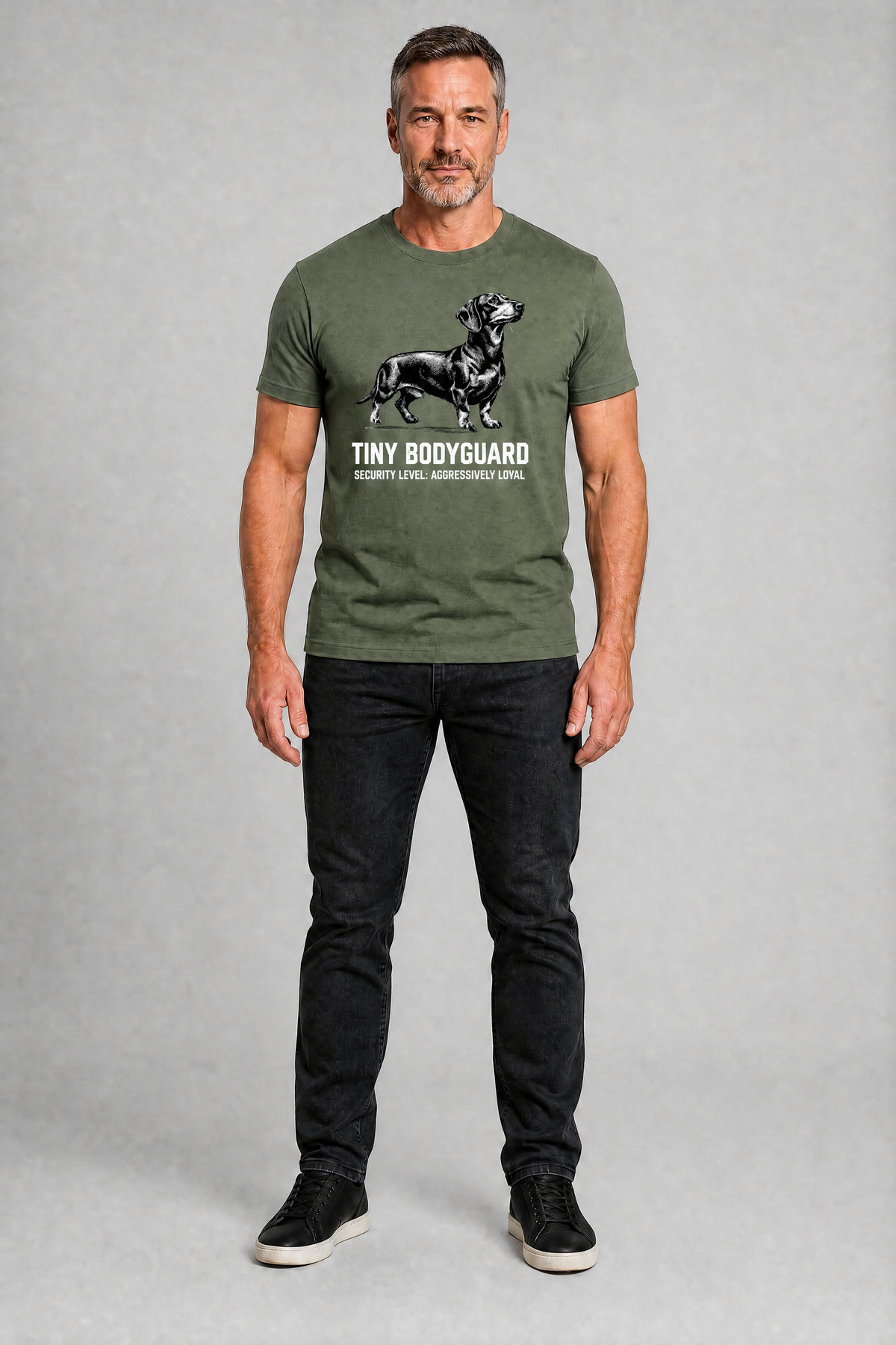 Man wearing a green t-shirt with a graphic and text, standing against a gray background
