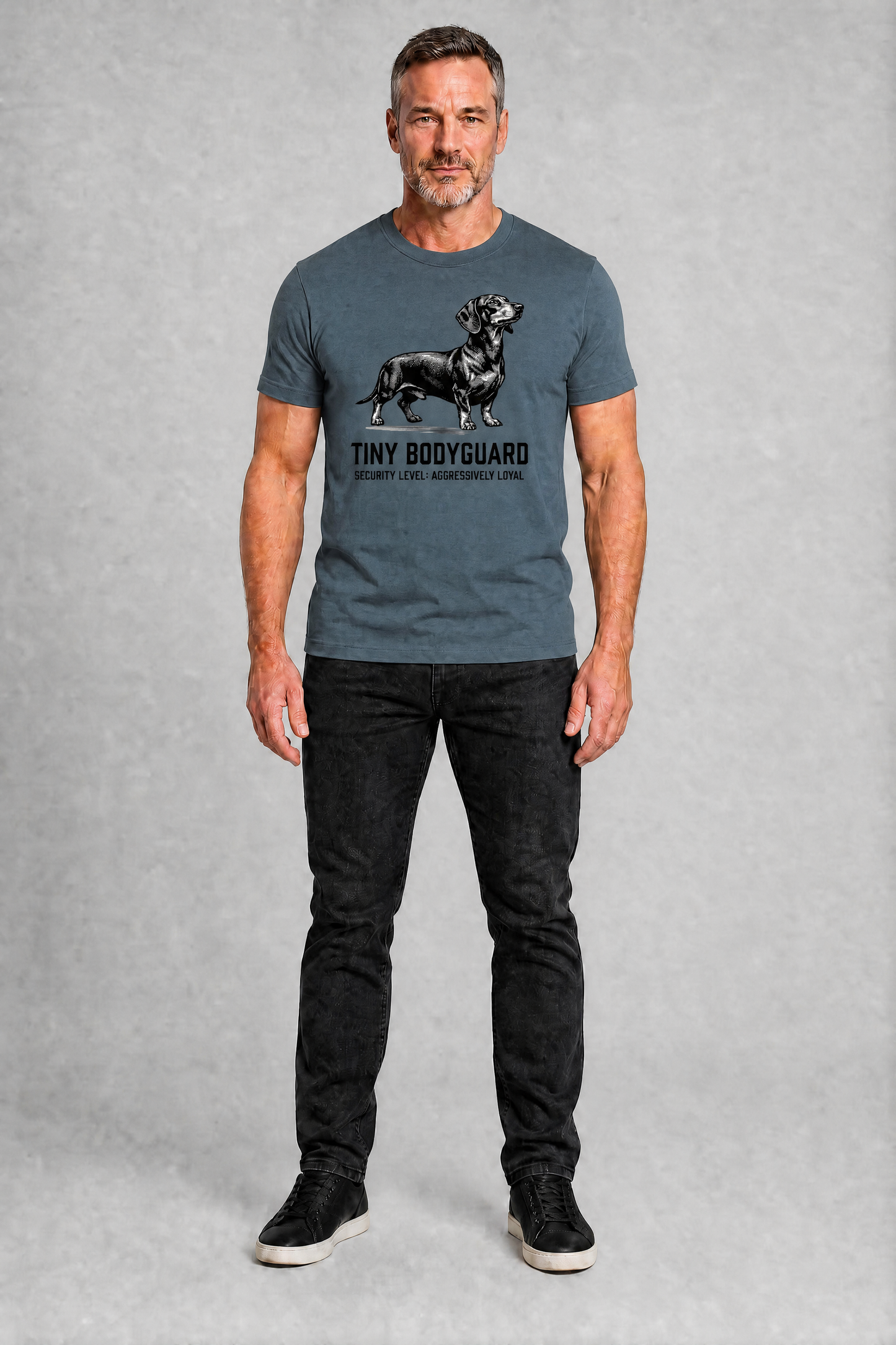 Man wearing a gray t-shirt with a graphic and text, standing against a plain background