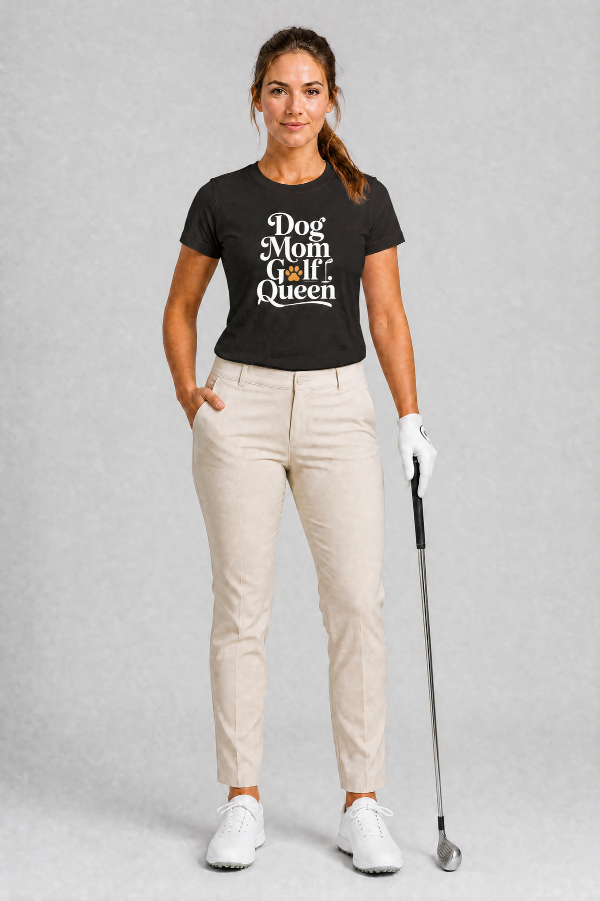 Woman wearing a navy t-shirt with 'Dog Mom Golf Queen' text, holding a golf club on a gray background