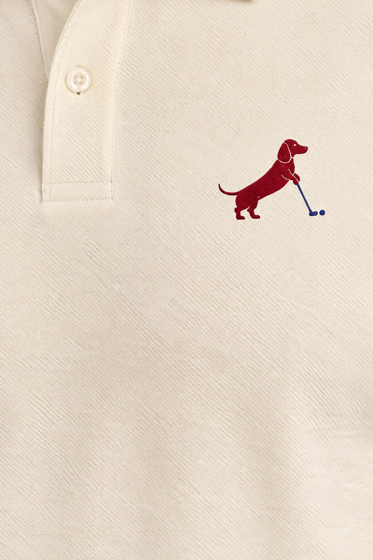 Close-up of collar and chest logo on apricot Putting dachshund golf polo. Color: Apricot