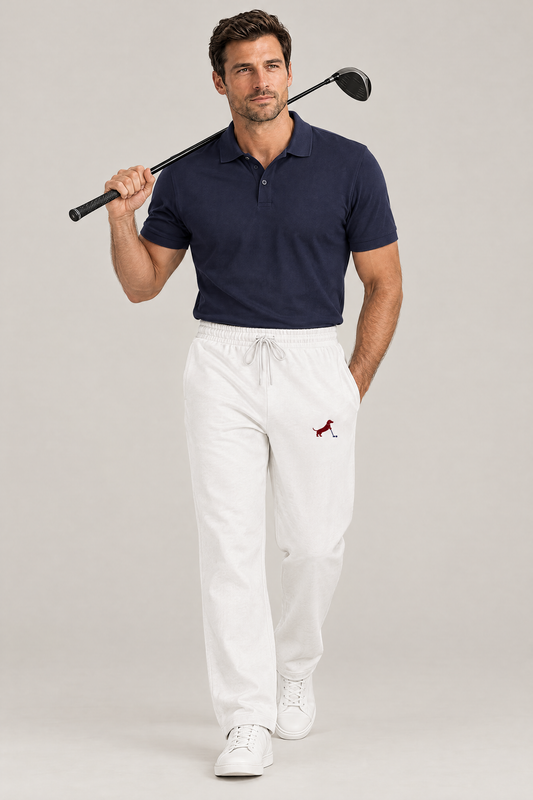 Man walking with a driver on his shoulder in white Putting dachshund golf sweatpants and a navy polo. Color: White