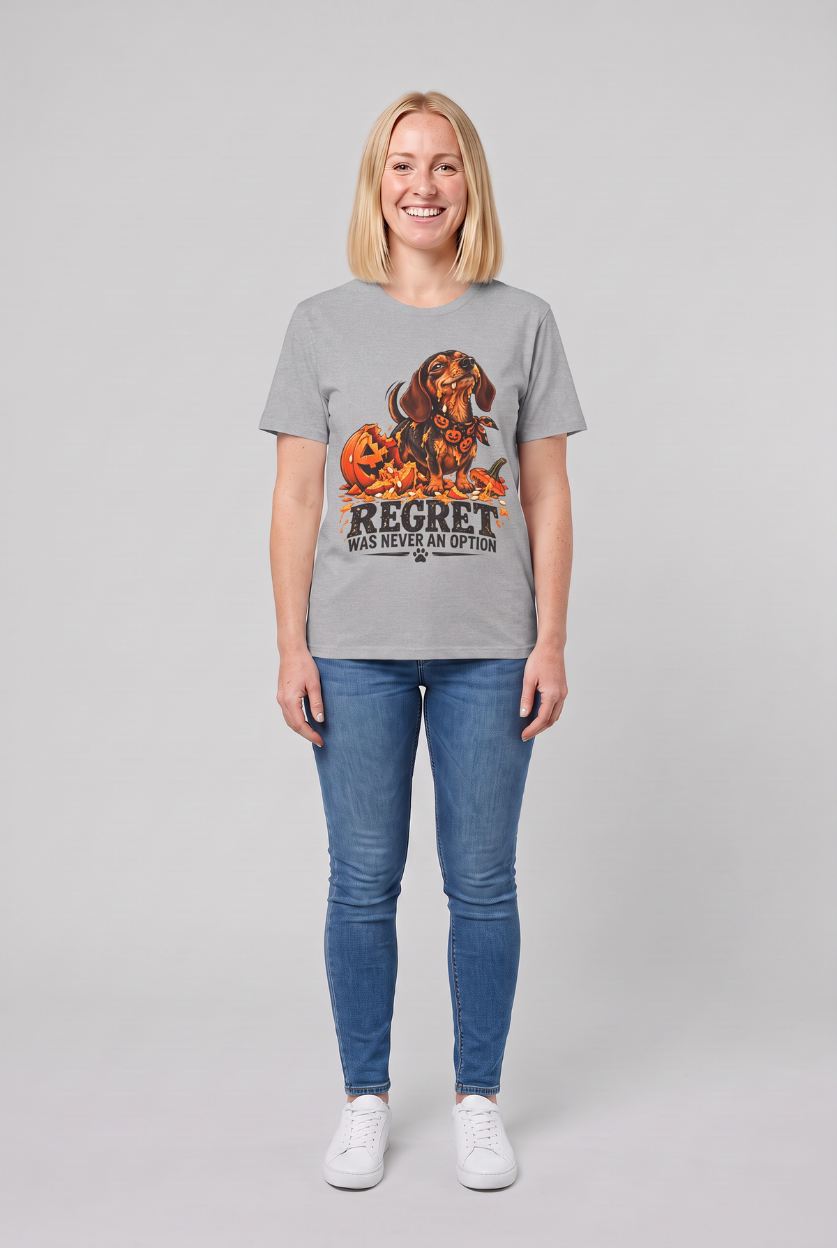 Woman wearing a sport grey funny dachshund Halloween t-shirt with a wiener dog next to a smashed jack-o-lantern and the text Regret Was Never An Option, front view