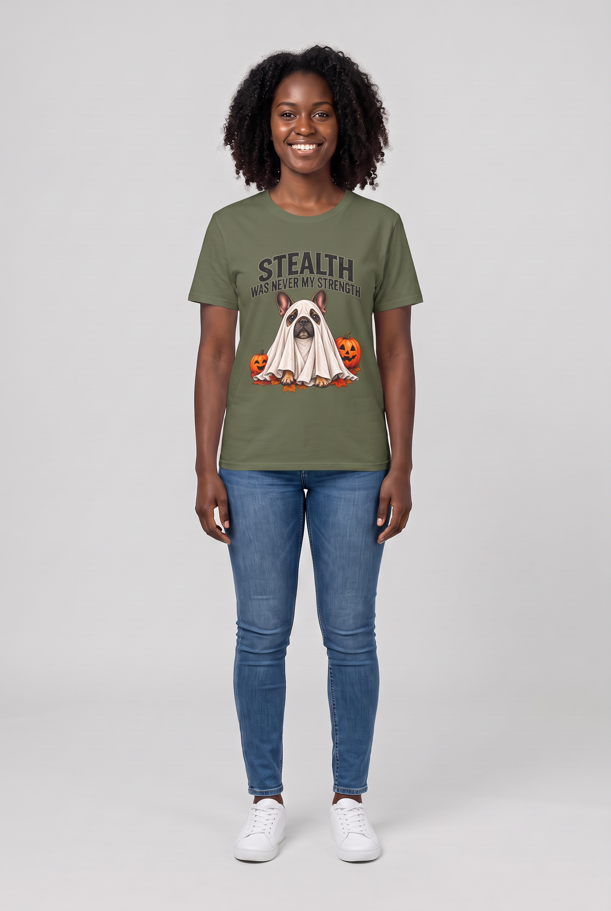 Woman wearing a military green French bulldog Halloween t-shirt with a Frenchie ghost and the text Stealth Was Never My Strength, front view