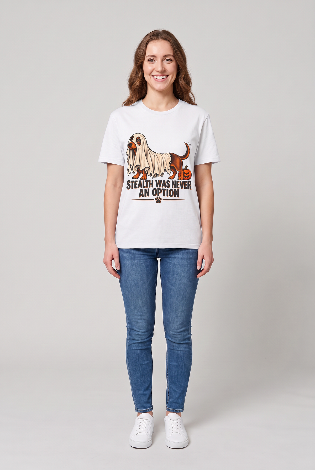 Woman wearing a white dachshund Halloween t-shirt with a wiener dog under a too-short ghost sheet and the text Stealth Was Never An Option, front view
