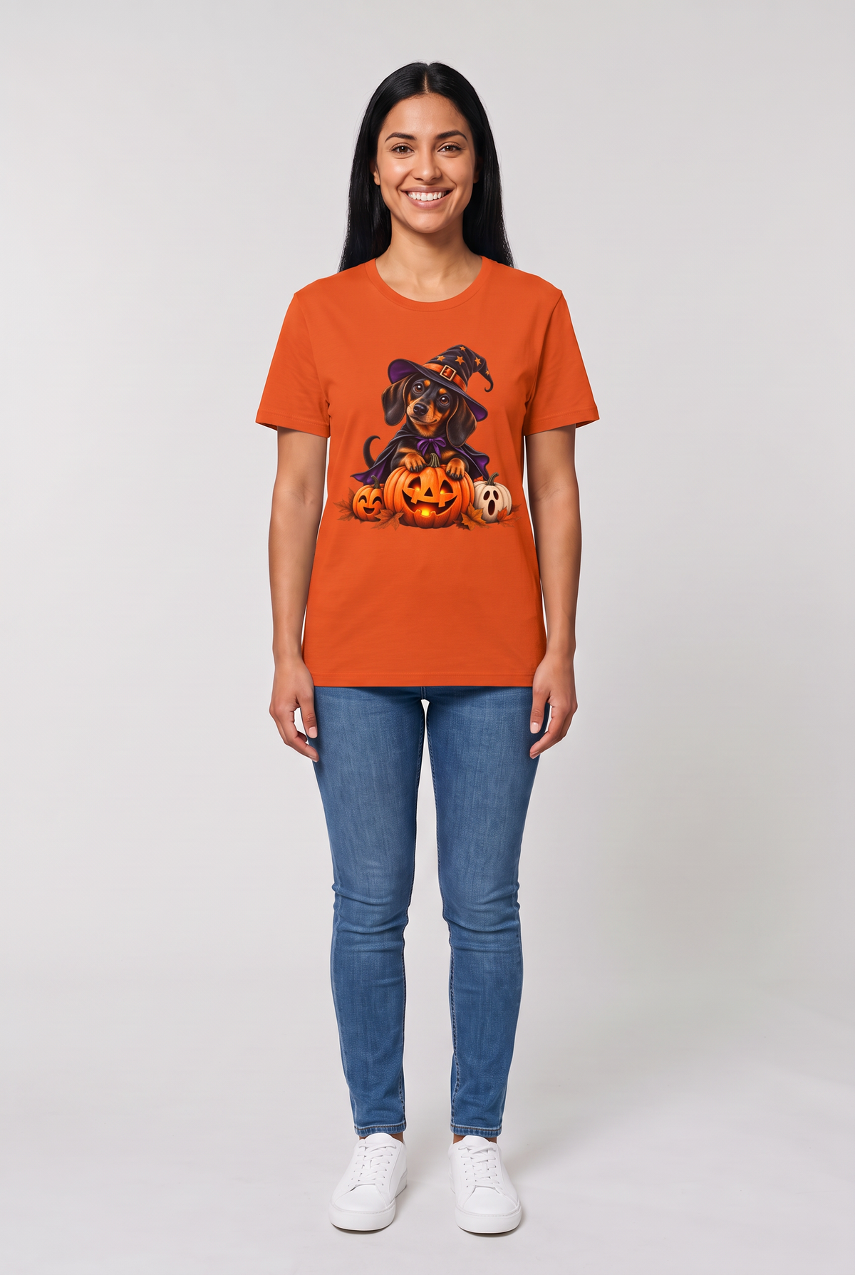 Woman wearing an orange dachshund witch Halloween t-shirt with a wiener dog in a witch hat and cape on a glowing jack-o-lantern, front view