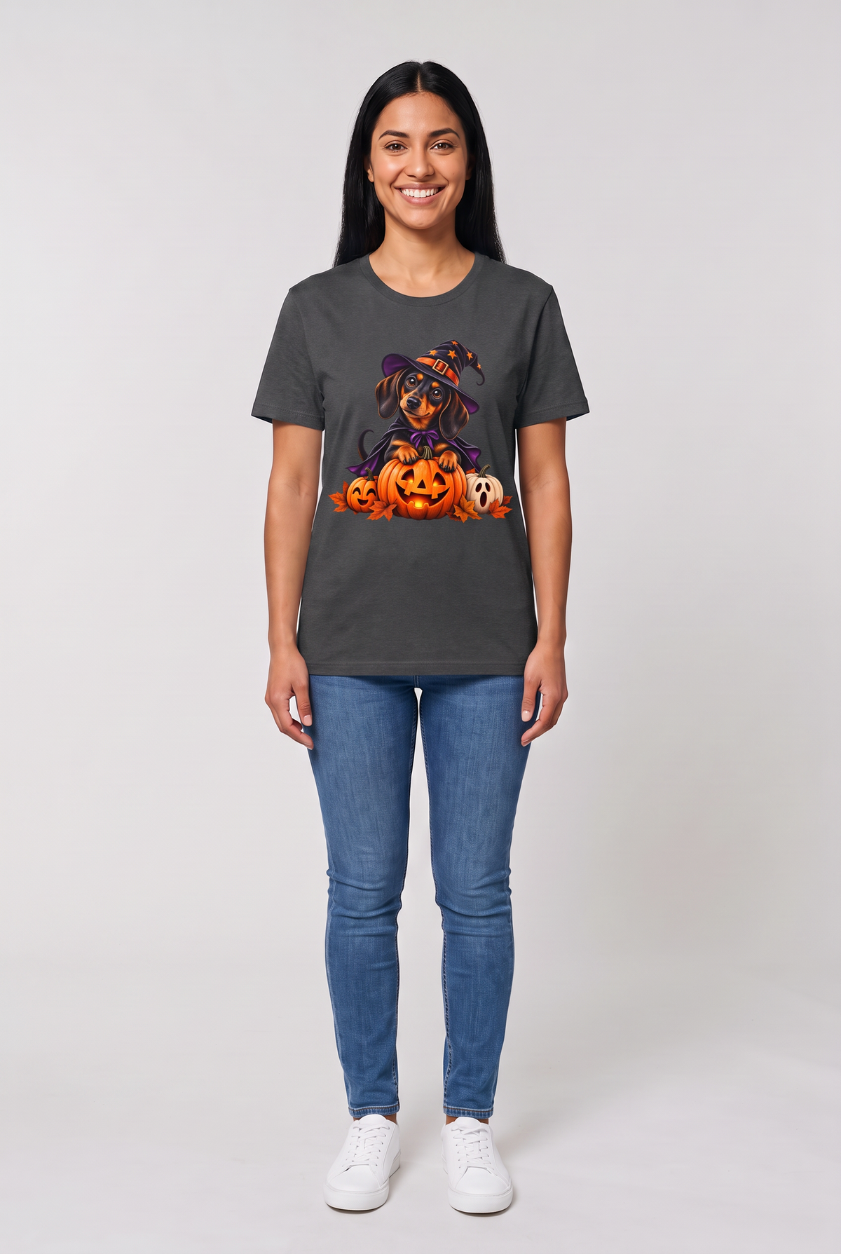 Woman wearing a dark heather dachshund witch Halloween t-shirt with a wiener dog in a witch hat and cape on a glowing jack-o-lantern, front view