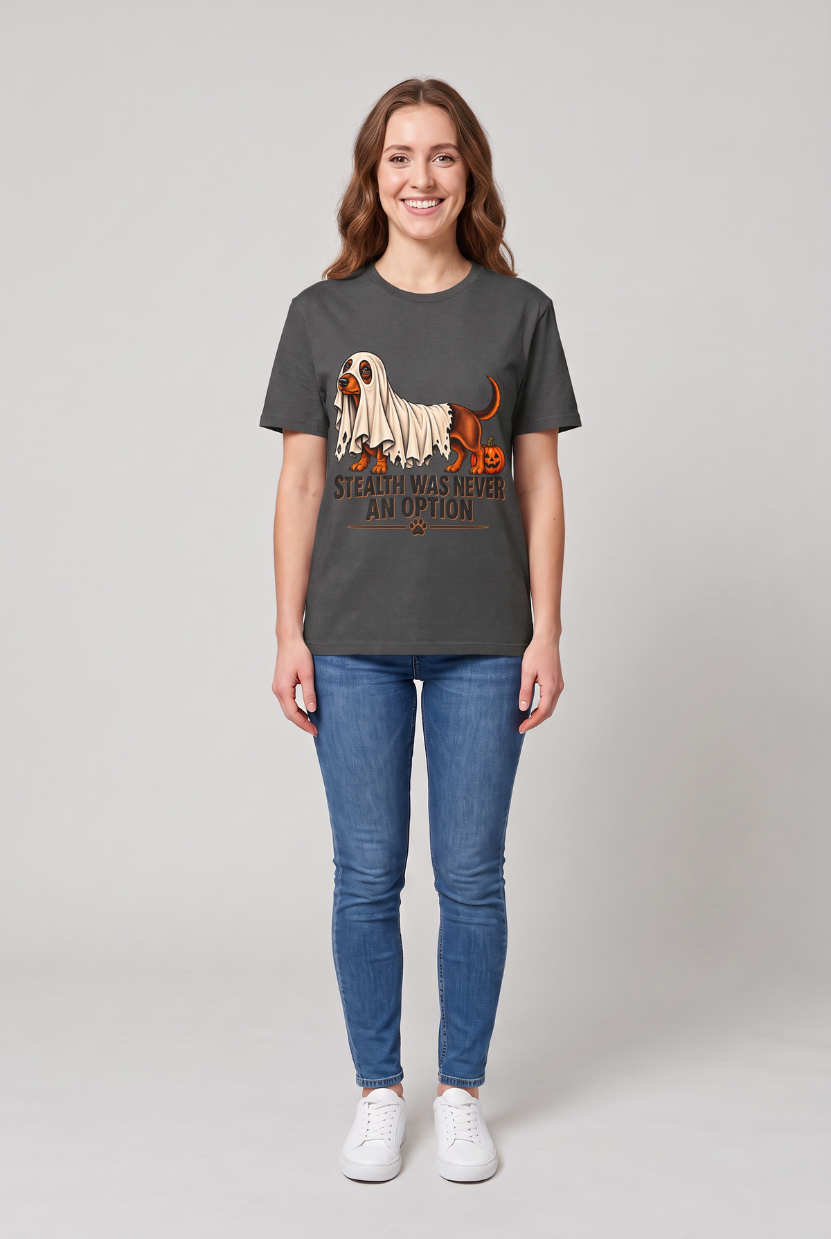 Woman wearing a dark heather dachshund Halloween t-shirt with a wiener dog under a too-short ghost sheet and the text Stealth Was Never An Option, front view