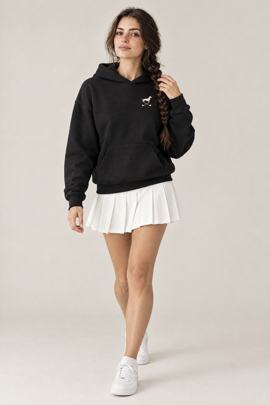 Woman walking in black Club & Swing dachshund golf hoodie with a white pleated tennis skirt, three-quarter view. Color: Black