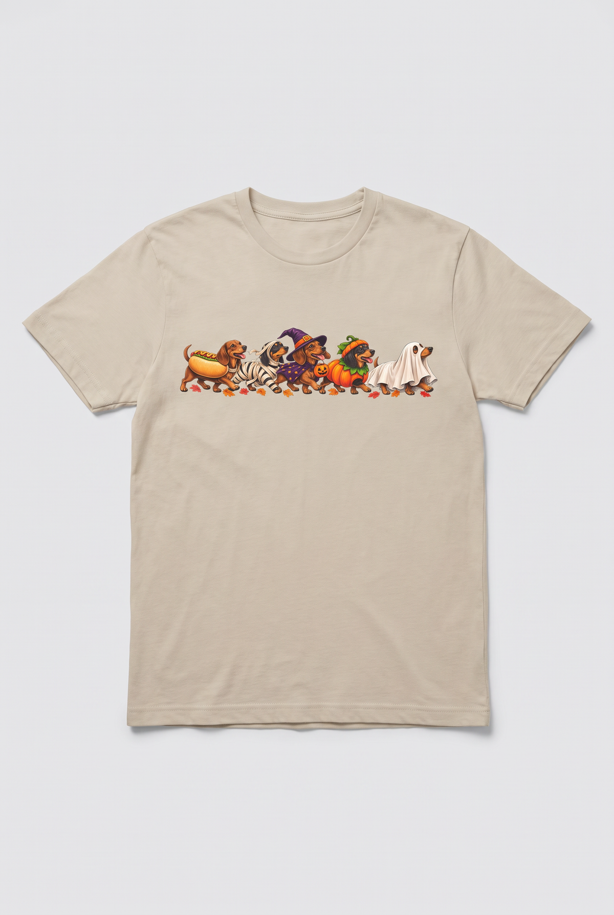 Flat lay of a sand wiener dog Halloween parade t-shirt with five dachshunds dressed as hot dog, mummy, witch, pumpkin and ghost