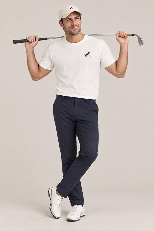 Smiling man in cream golf cap and white Putting dachshund golf t-shirt holding a golf club behind his shoulders, full-body studio look. Color: White