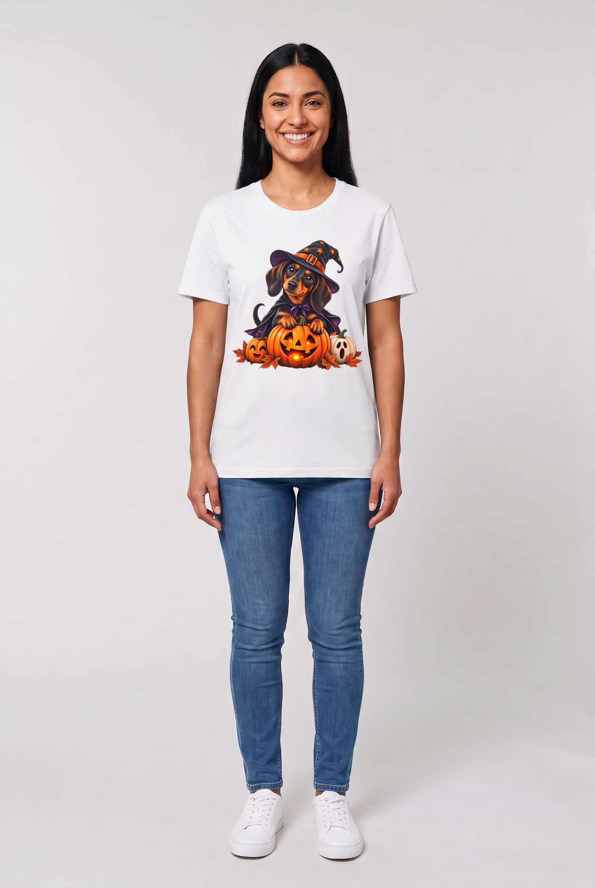 Woman wearing a white dachshund witch Halloween t-shirt with a wiener dog in a witch hat and cape on a glowing jack-o-lantern, front view