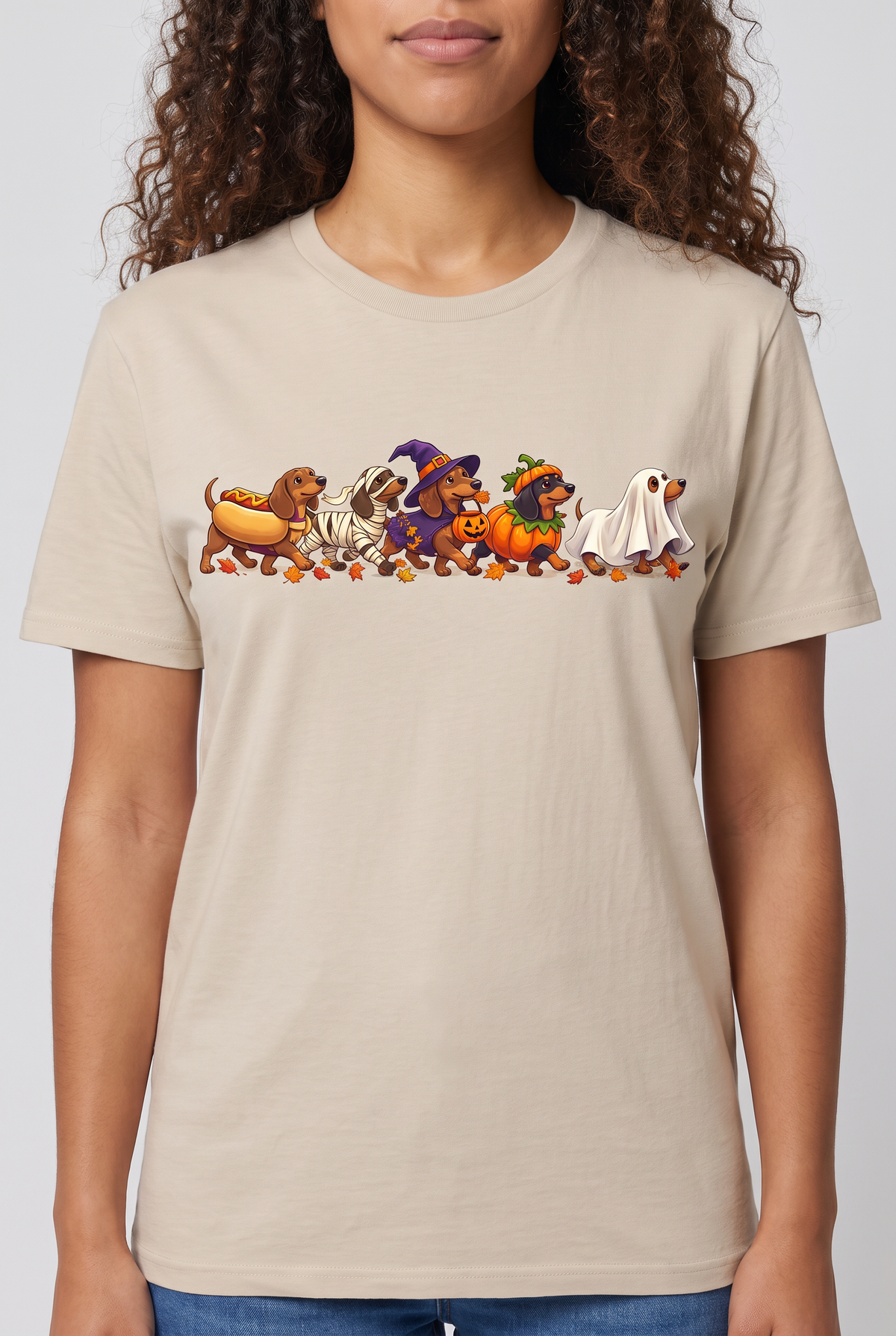 Close-up of the chest print on a sand wiener dog Halloween parade t-shirt with five dachshunds dressed as hot dog, mummy, witch, pumpkin and ghost