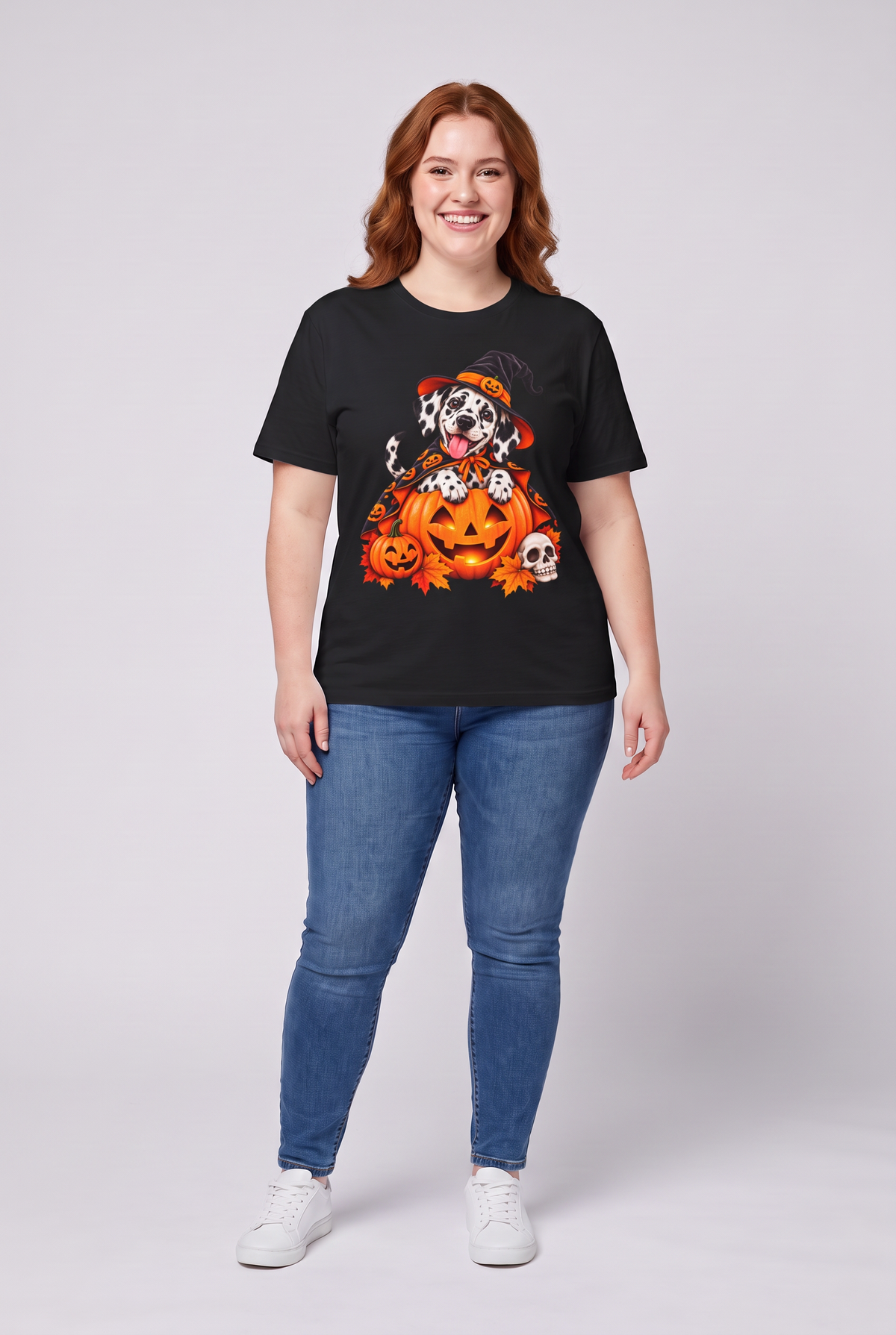 Woman wearing a black Dalmatian witch Halloween t-shirt with a Dalmatian in a witch hat and pumpkin cape on a jack-o-lantern, front view