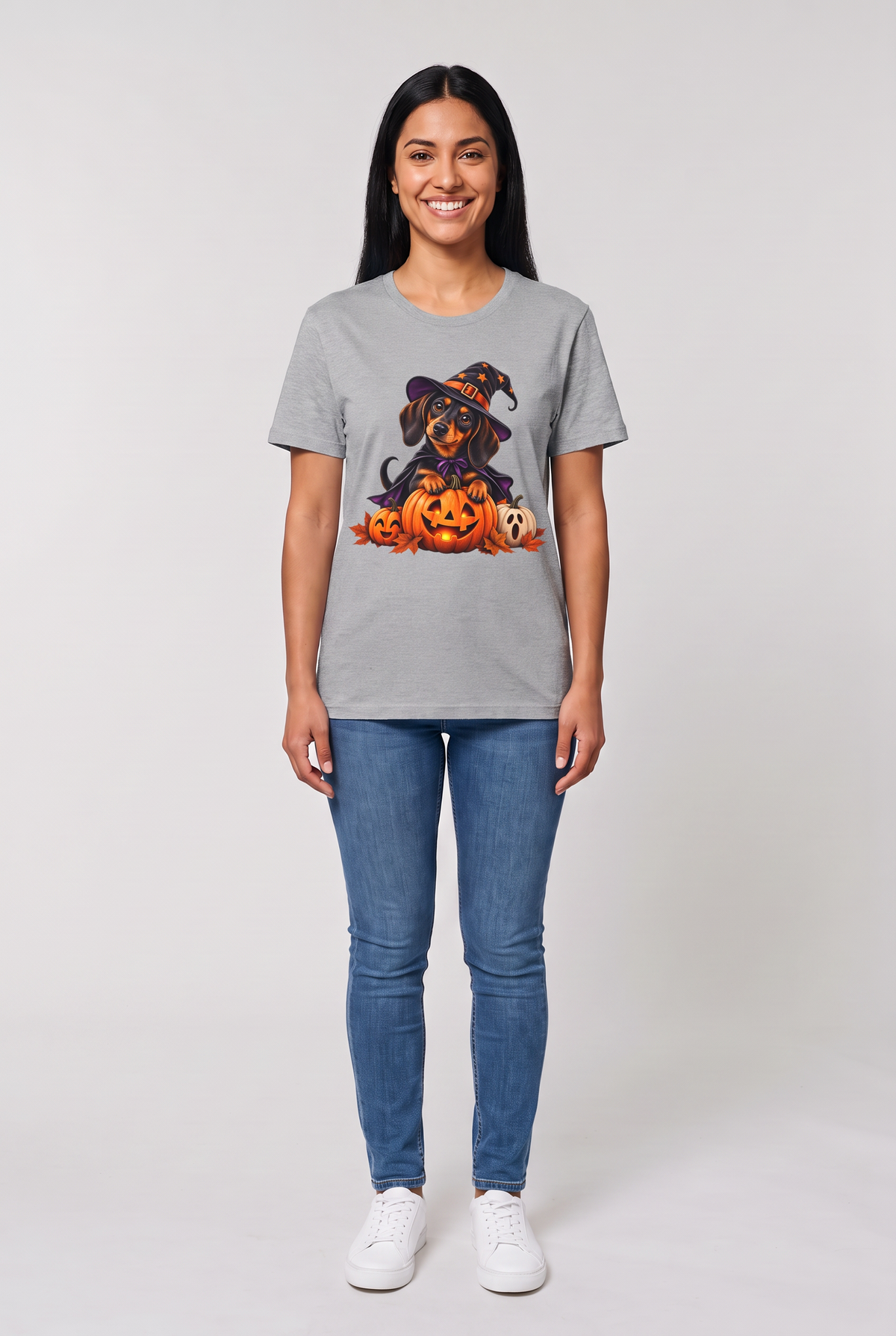 Woman wearing a sport grey dachshund witch Halloween t-shirt with a wiener dog in a witch hat and cape on a glowing jack-o-lantern, front view