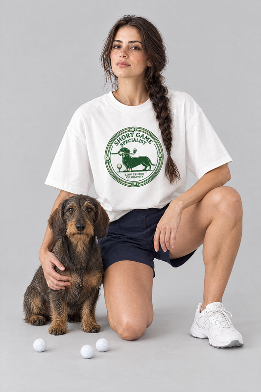 Woman kneeling with a wire-haired dachshund in the white Short Game Specialist Dachshund Golf Tee. Color: White