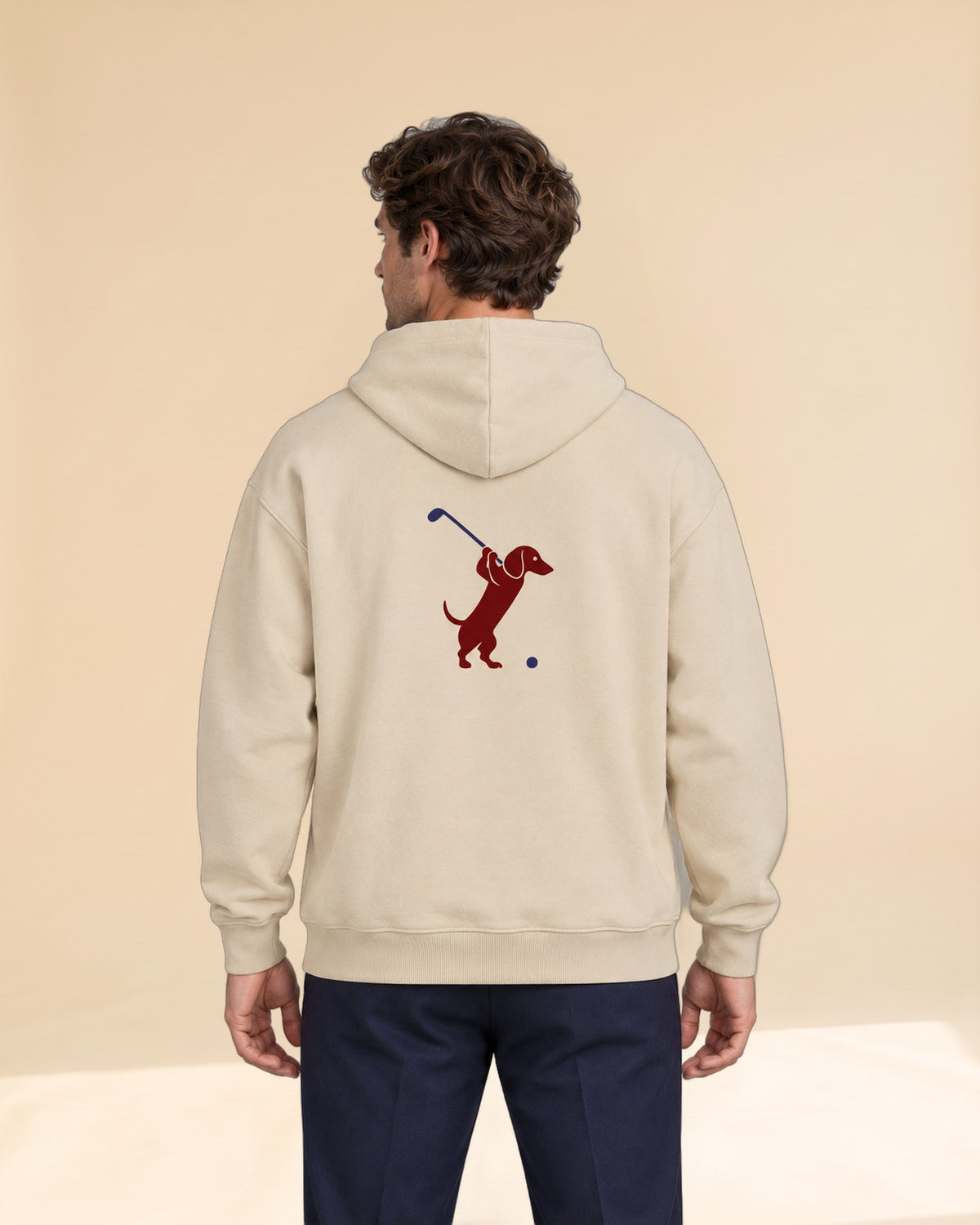 Man wearing Club & Swing dachshund golf hoodie, back studio view. Color: Apricot