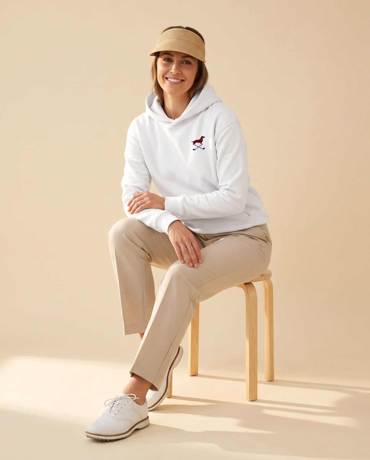 Woman wearing Club & Swing dachshund golf hoodie, full-body studio look. Color: White