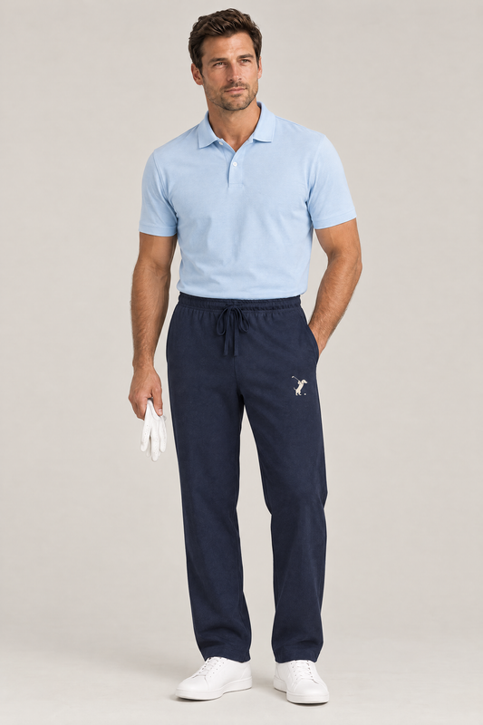 Man holding a white golf glove in navy blue Swing dachshund golf sweatpants with the small cream dachshund golfer on the thigh and a light blue polo. Color: Navy Blue