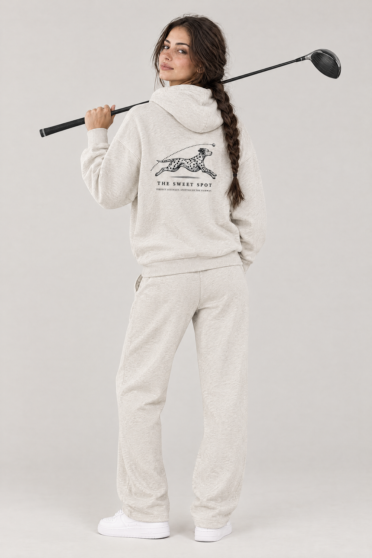 Woman with a driver over her shoulder, back view of The Sweet Spot Dalmatian golf hoodie in Oat Gray with the large back print. Color: Oat Gray