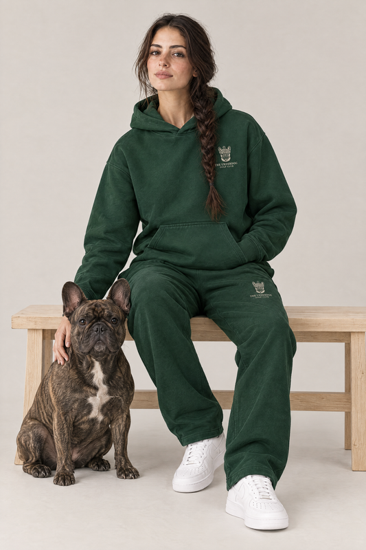 Woman sitting on a wooden bench with a brindle French Bulldog in The Marshal French Bulldog golf hoodie and sweatpants in Blackish Green. Color: Blackish Green