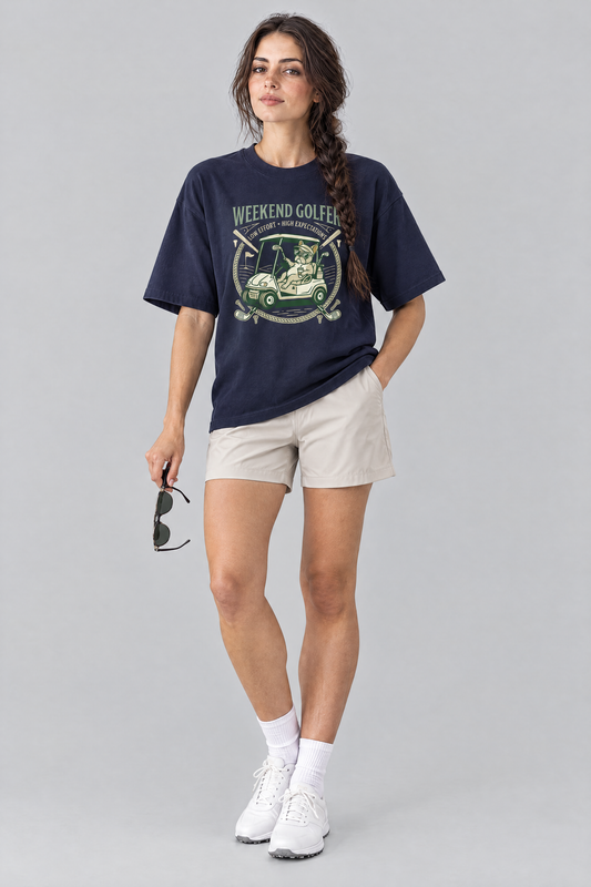Woman wearing the Weekend Golfer French Bulldog Golf Tee in navy with stone golf shorts, holding sunglasses. Color: Navy