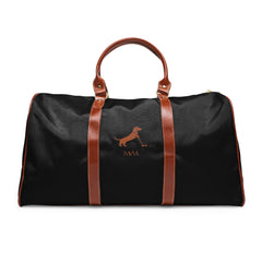 Color: Black. Putting Dachshund golf travel bag in black with a brown putting dachshund and MVM monogram on the front, brown PU handles, front view.