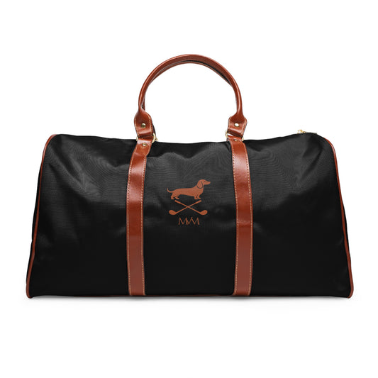 Color: Black. Club Mark golf travel bag in black with a brown Dachshund with crossed golf clubs and MVM monogram on the front, brown PU handles, front view.