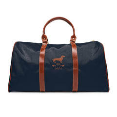Color: Navy. Club Mark golf travel bag in navy with a brown Dachshund with crossed golf clubs and MVM monogram on the front, brown PU handles, front view.