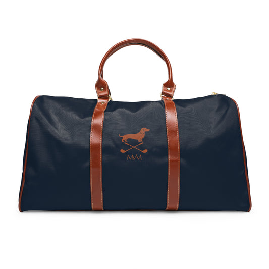 Color: Navy. Club Mark golf travel bag in navy with a brown Dachshund with crossed golf clubs and MVM monogram on the front, brown PU handles, front view.
