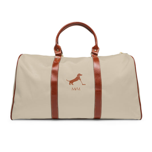 Color: Beige. Putting Dachshund golf travel bag in beige with a brown putting dachshund and MVM monogram on the front, brown PU handles, front view.