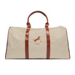 Color: Beige. Putting Dachshund golf travel bag in beige with a brown putting dachshund and MVM monogram on the front, brown PU handles, front view.
