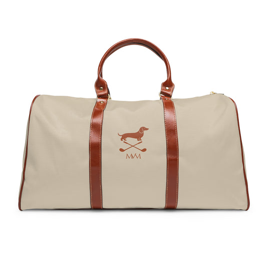 Color: Beige. Club Mark golf travel bag in beige with a brown Dachshund with crossed golf clubs and MVM monogram on the front, brown PU handles, front view.
