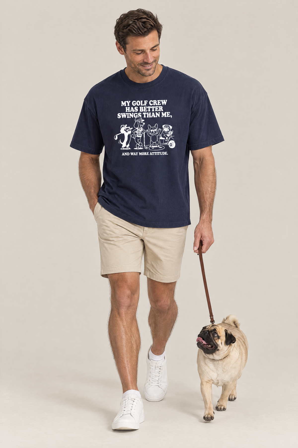 Man walking a pug on a leash in the navy Better Swings Dog Golf Tee. Color: Navy