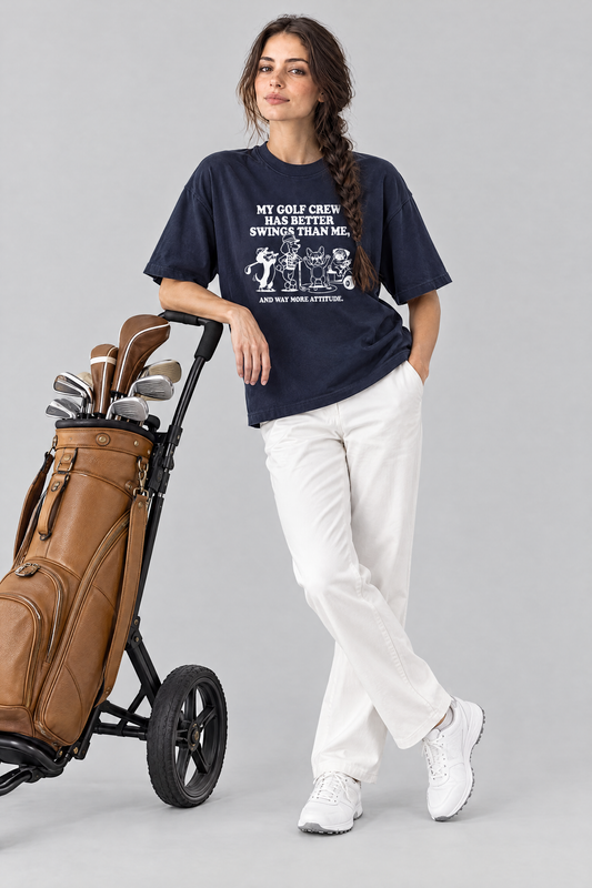 Woman leaning on a golf push trolley in the navy Better Swings Dog Golf Tee and white trousers. Color: Navy