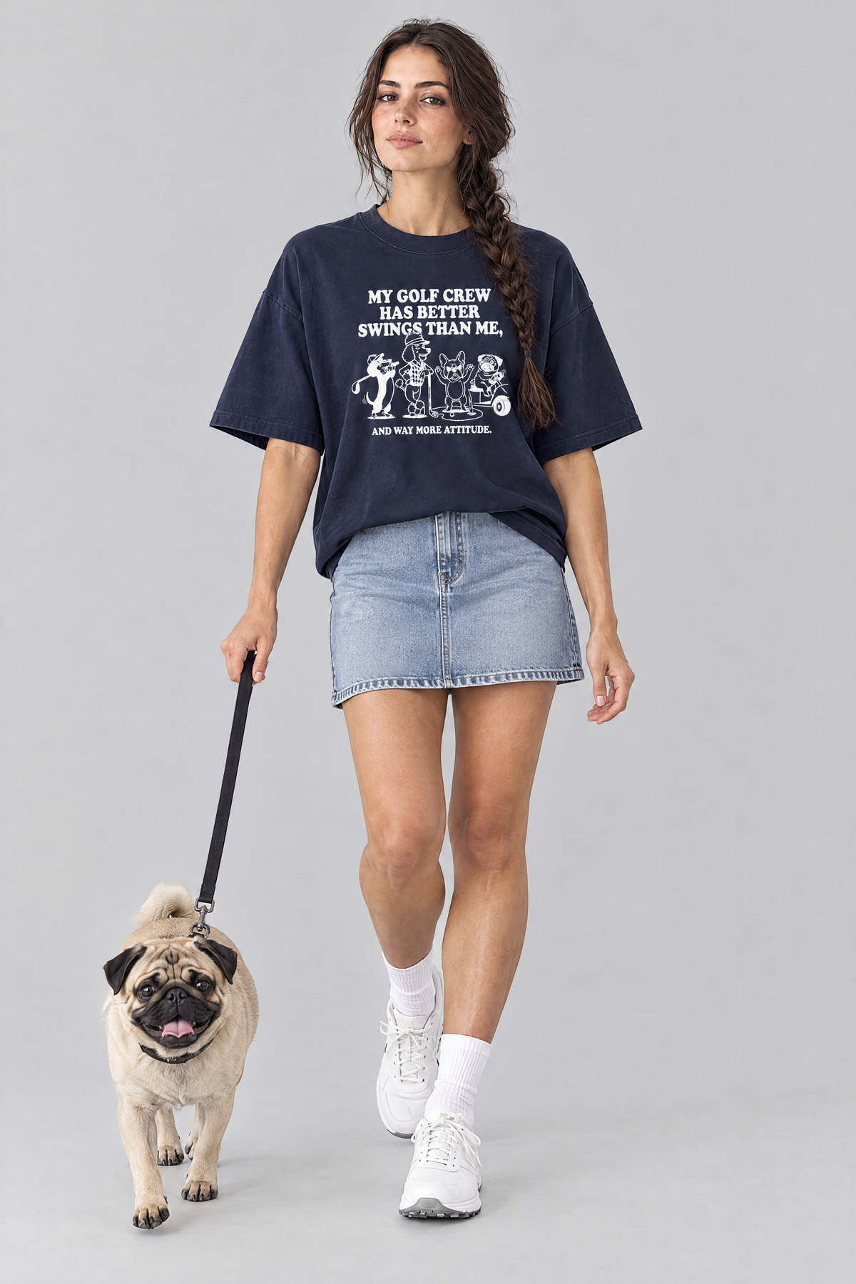 Woman walking a pug on a leash in the navy Better Swings Dog Golf Tee. Color: Navy