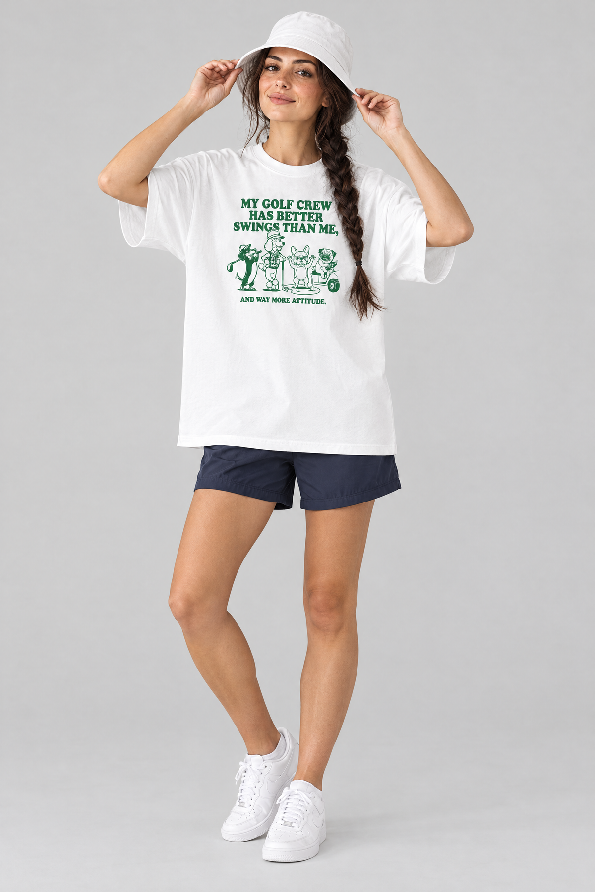 Woman putting on a white bucket hat in the white Better Swings Dog Golf Tee with navy shorts. Color: White