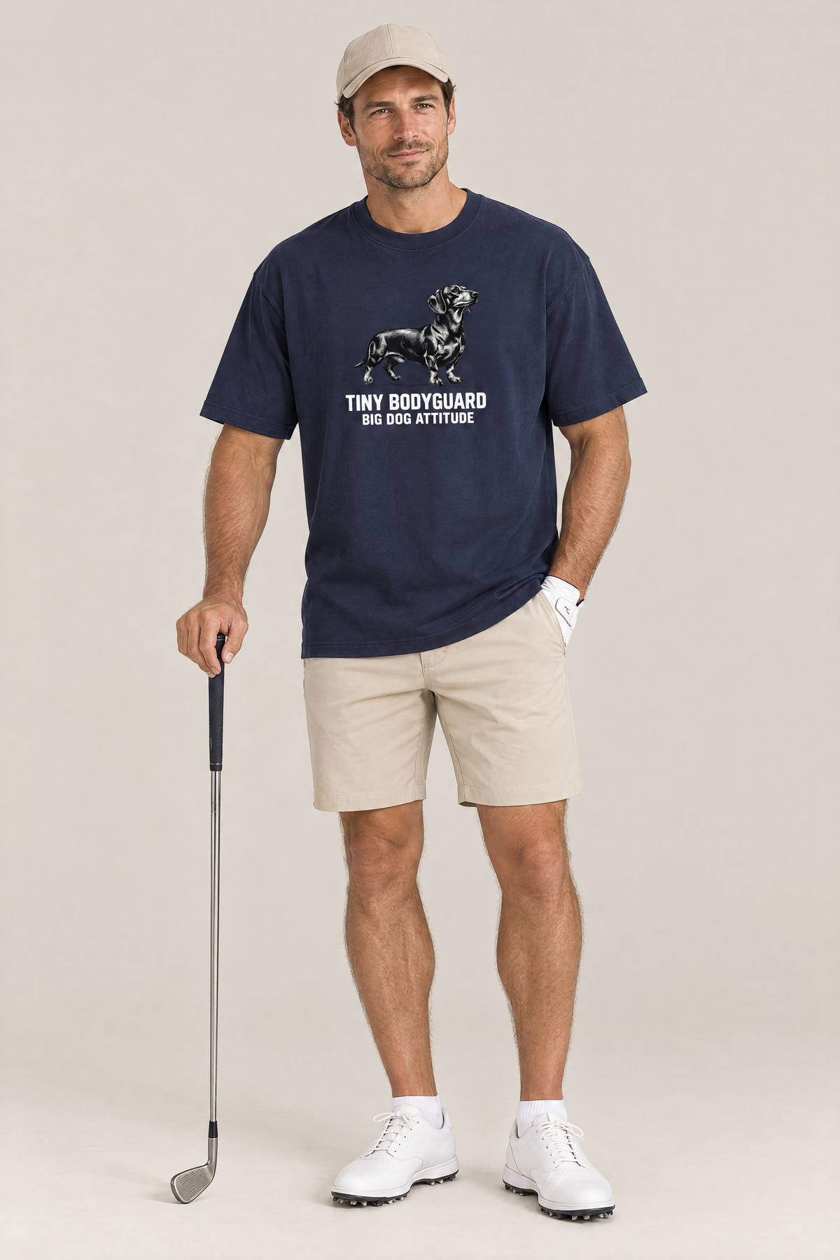 Man in a beige cap holding a golf club in the navy Big Dog Attitude Dachshund Tee. Color: Navy