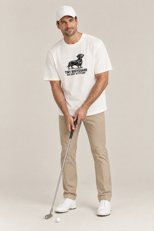 Man in a white cap lining up a golf shot in the white Big Dog Attitude Dachshund Tee. Color: White