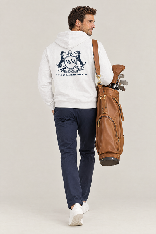Man carrying a tan leather golf bag, back view of the white Club Crest hoodie with the large navy Golf & Dachshund Club crest, worn with navy chinos