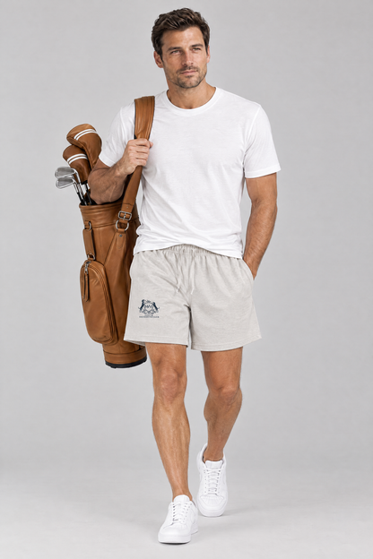 Man walking with a tan leather golf bag in oat gray Club Crest shorts and a white tee. Color: Oat Gray
