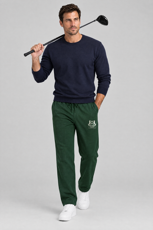 Man walking with a driver over his shoulder in blackish green Club Crest sweatpants and a navy sweater. Color: Blackish Green