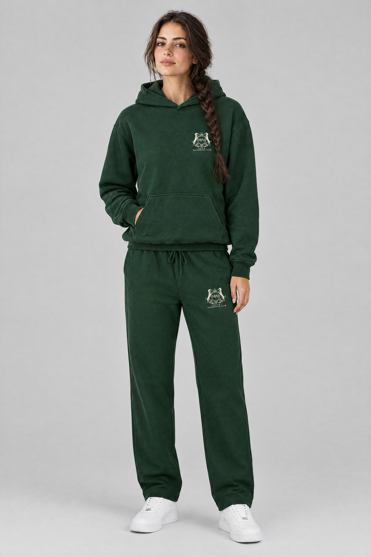 Woman in a matching blackish green set of Club Crest hoodie and sweatpants, both with the small cream crest. Color: Blackish Green