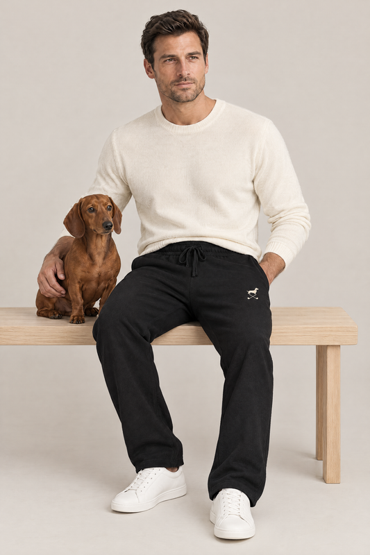 Man sitting on a wooden bench with a red dachshund in black Club Mark dachshund golf sweatpants and a cream knit sweater. Color: Black