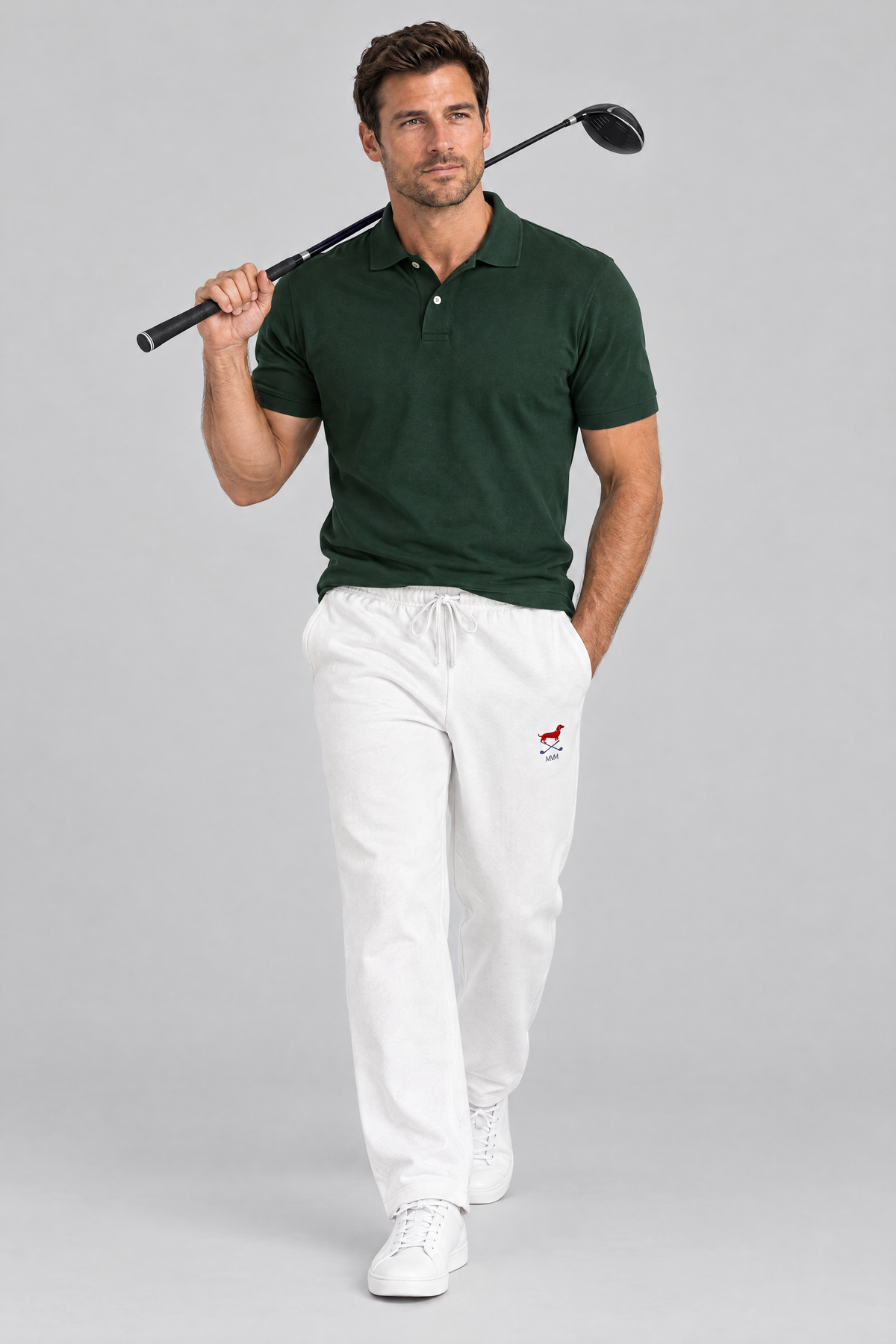 Man walking with a driver over his shoulder in white Club Mark dachshund golf sweatpants and a dark green polo. Color: White