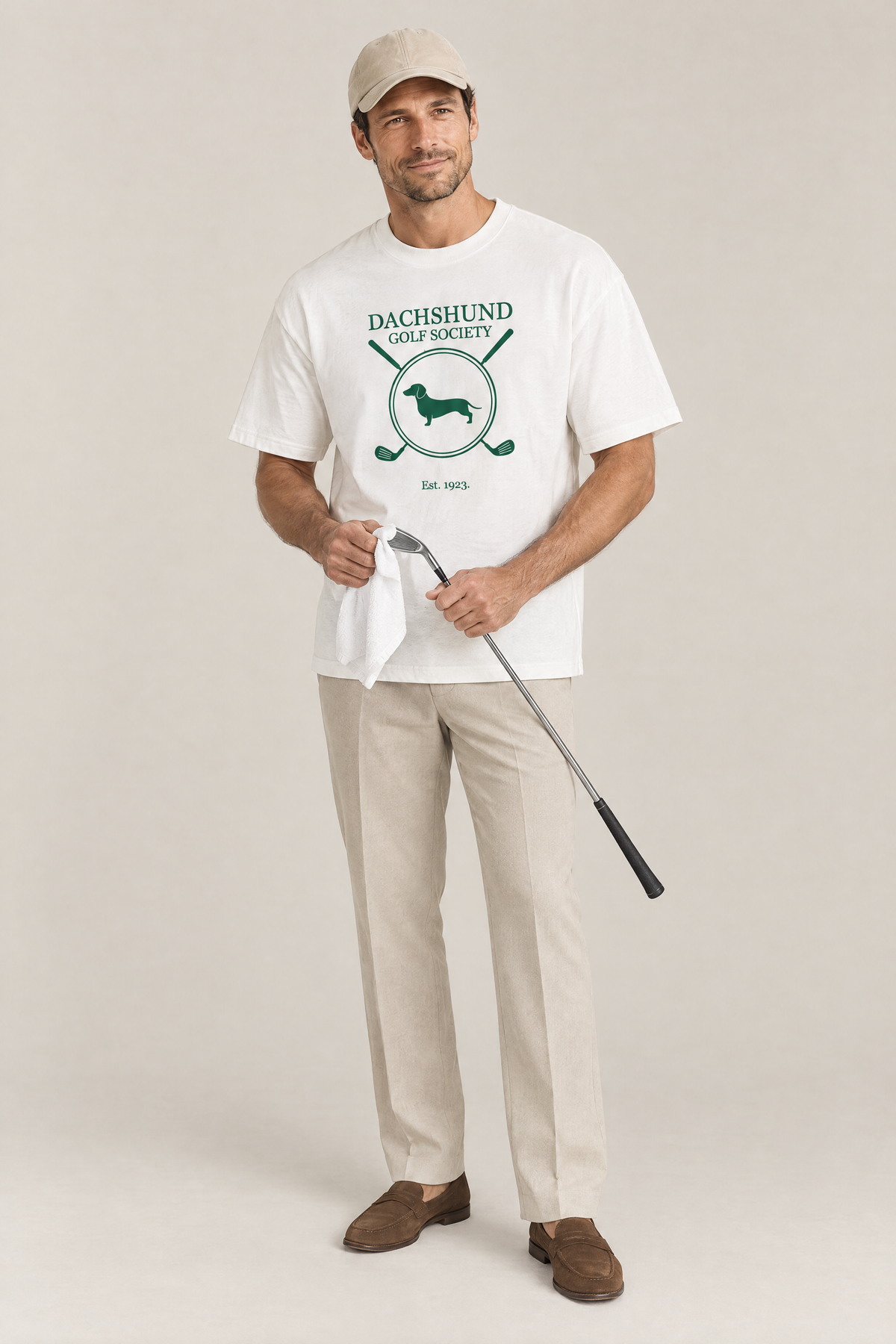 Man cleaning a golf club with a towel in the white Dachshund Golf Society Tee. Color: White